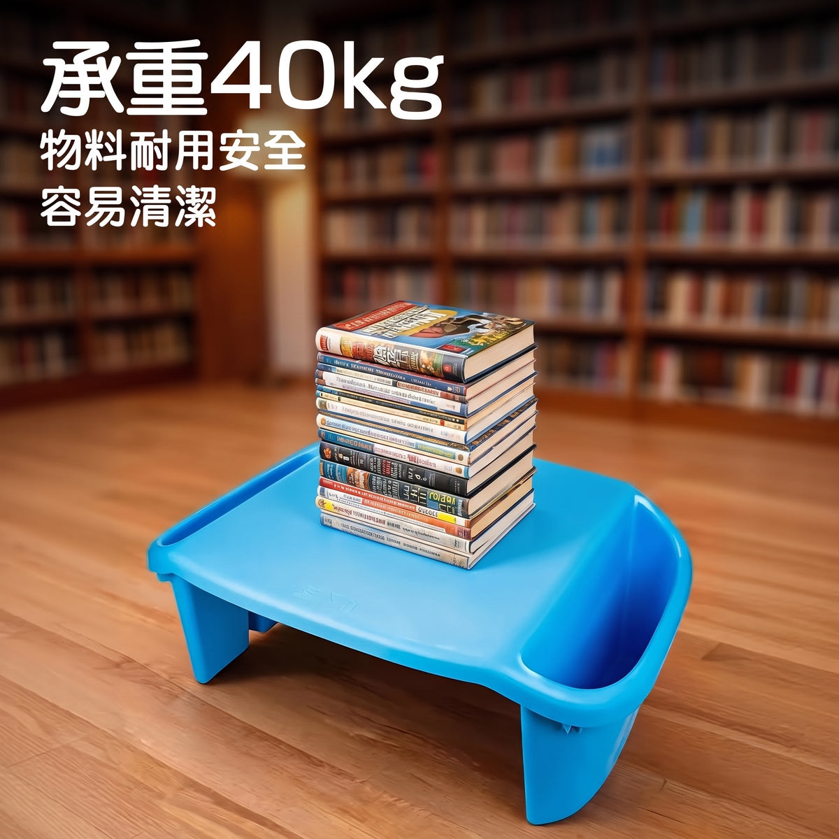 A blue plastic low table with a stack of books on top, set on a wooden floor in front of a blurred bookshelf background. White Chinese text in the upper left reads '承重40kg' and additional product feature text below.